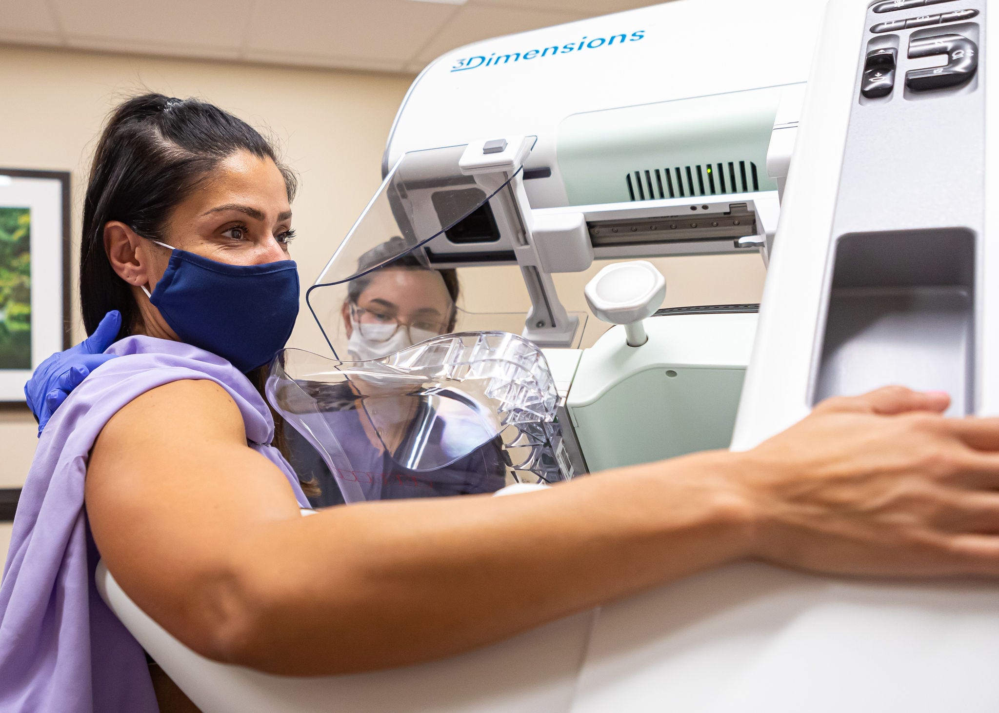 young dark haired woman in purple gown getting a mamogram
