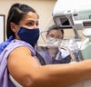 young dark haired woman in purple gown getting a mamogram