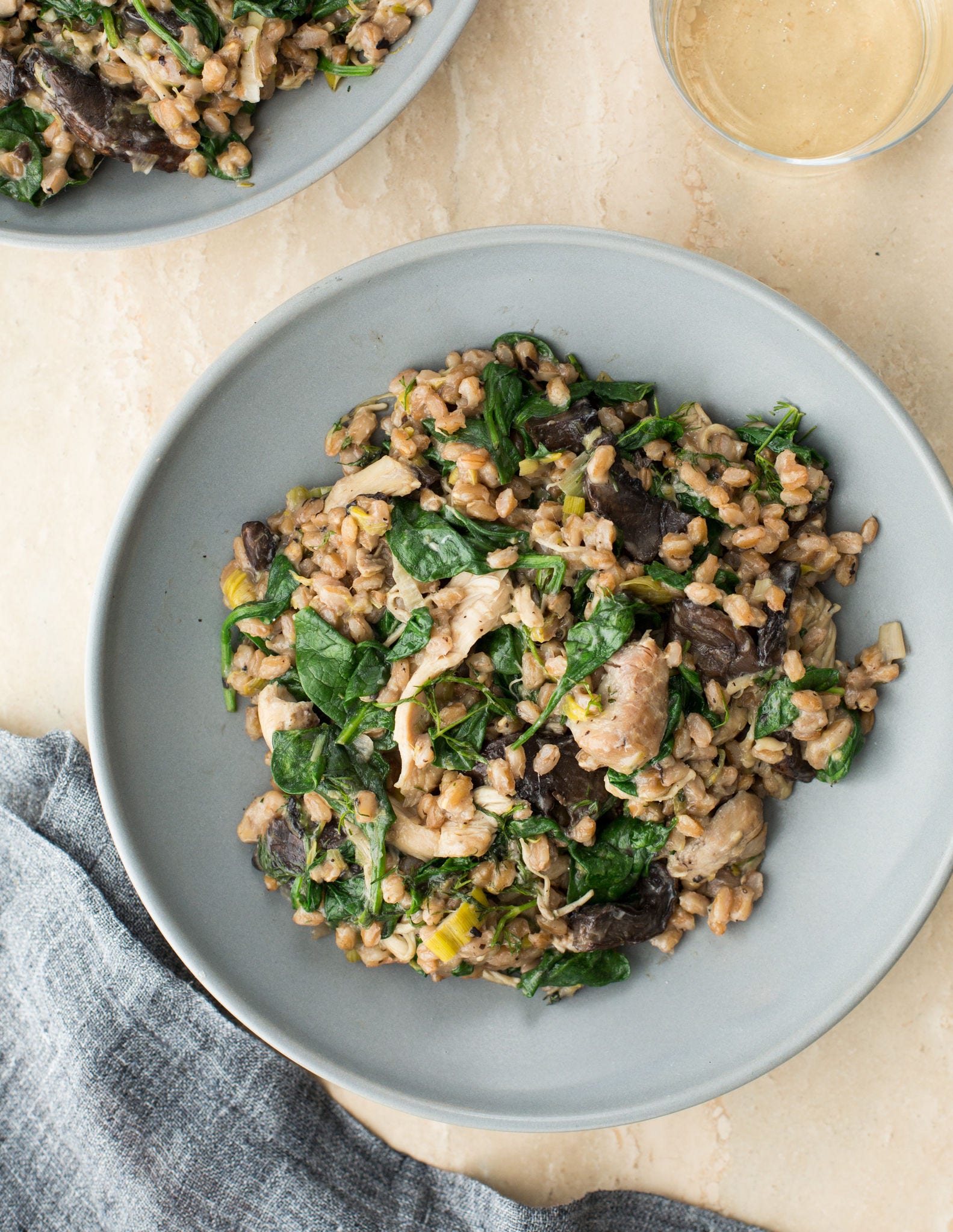 Seen from above, a white bowl holds farro made with chicken, portobello mushrooms, and spinach.