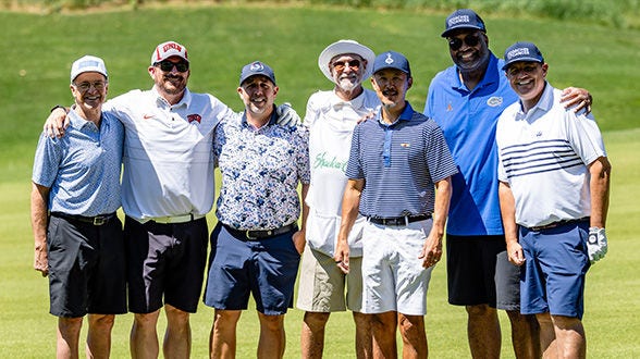 Group of men posing together on a golf course.