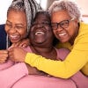 three black women smiling and hugging