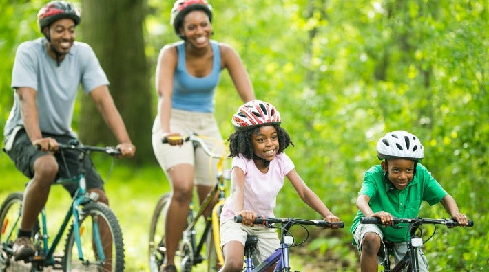 African American family cycling on a forest trail.