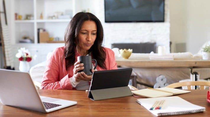 woman sitting at a table with computer and papers in her home