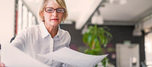 woman sorting through paperwork at office desk