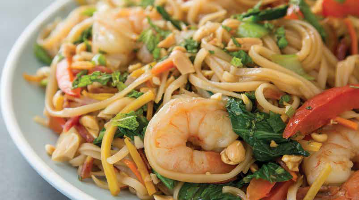 rice noodles with shrimp, bok choy and mint on a white plate