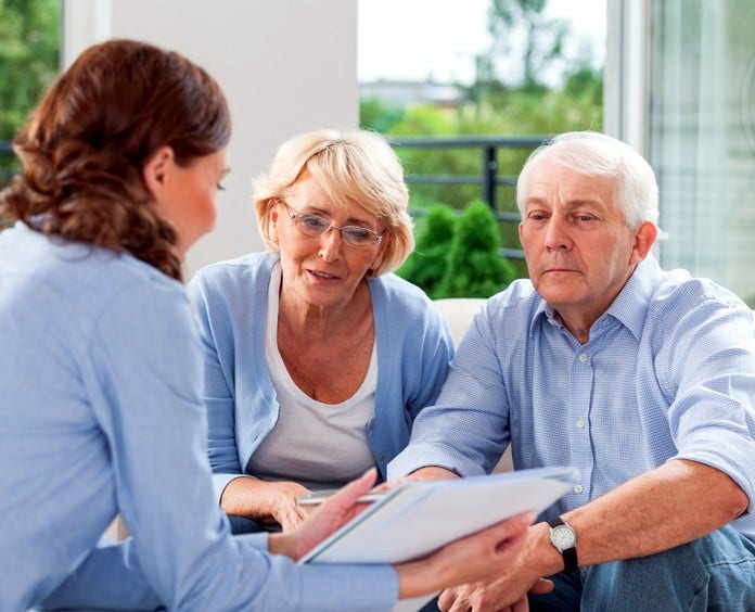 Cheerful senior couple having meeting with financial advisor or insurance agent at home.