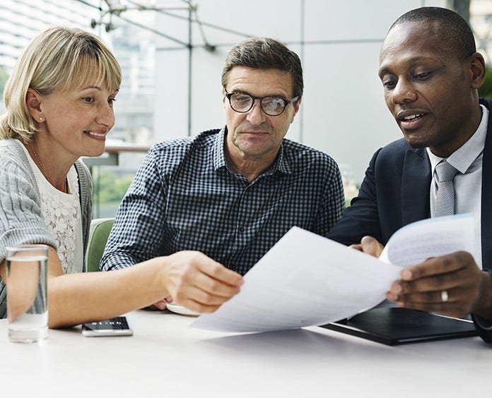 3 colleagues discussing paperwork during meeting