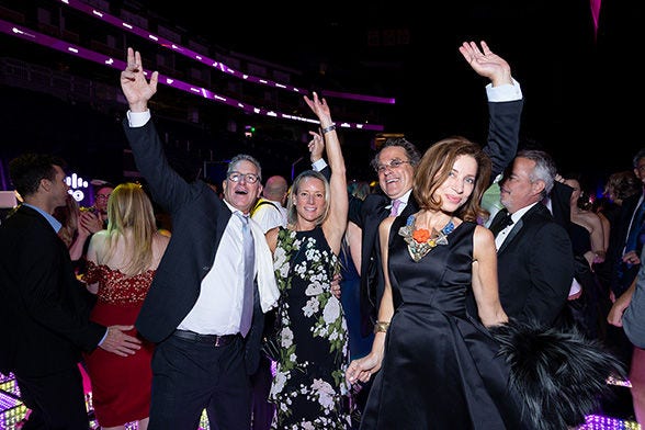 Group of people in formal attire dancing and celebrating at an event.