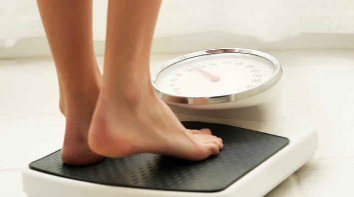 close up of woman's feet stepping onto a bathroom scale