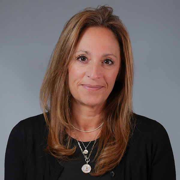 Professional headshot of a person in a black top against a gray background.