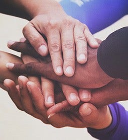 A closeup shot of multi-racial hands stacked on top of one another.