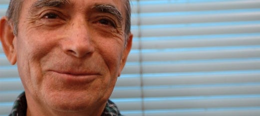 smiling senior man in front of blind covered window