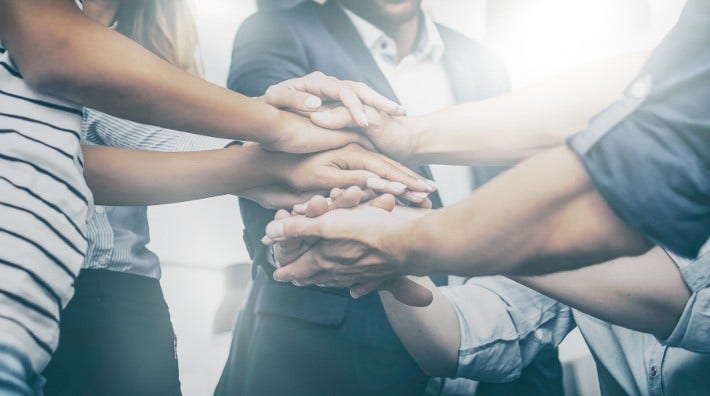 close up of people stacking their hands one on top of the other