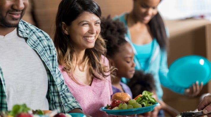 woman holds a plate of fruit and salad at a buffet table