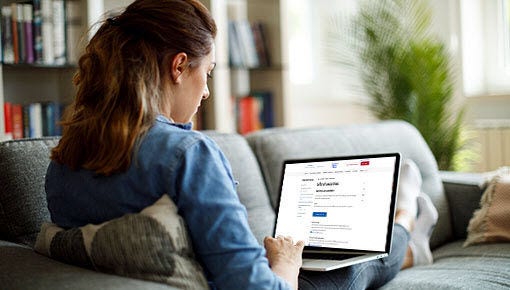 white woman looking at laptop while sitting on couch