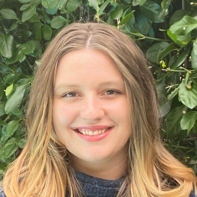 young woman with blonde hair, parted in middle, denim top