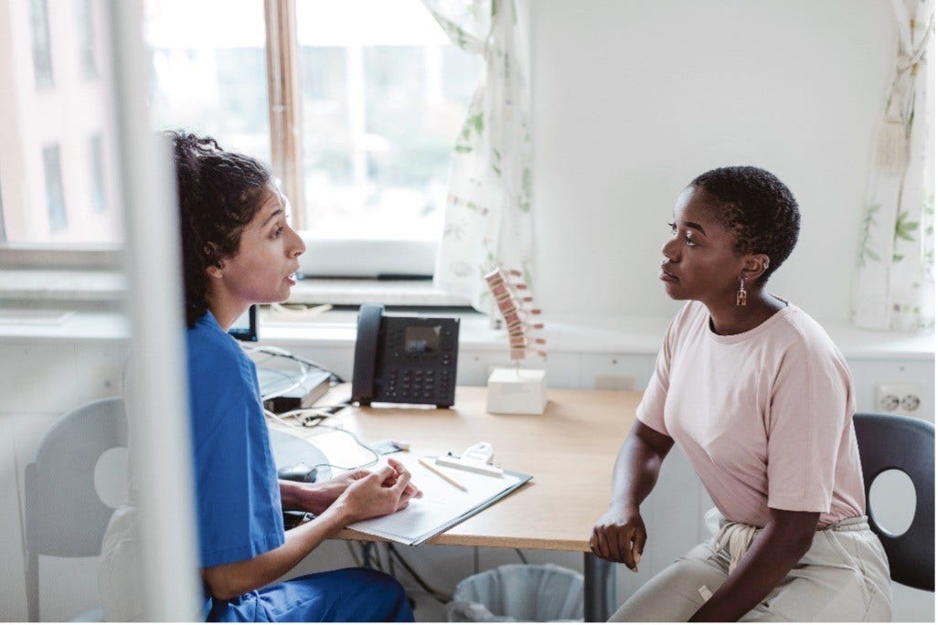 White nurse and black patient sitting at table