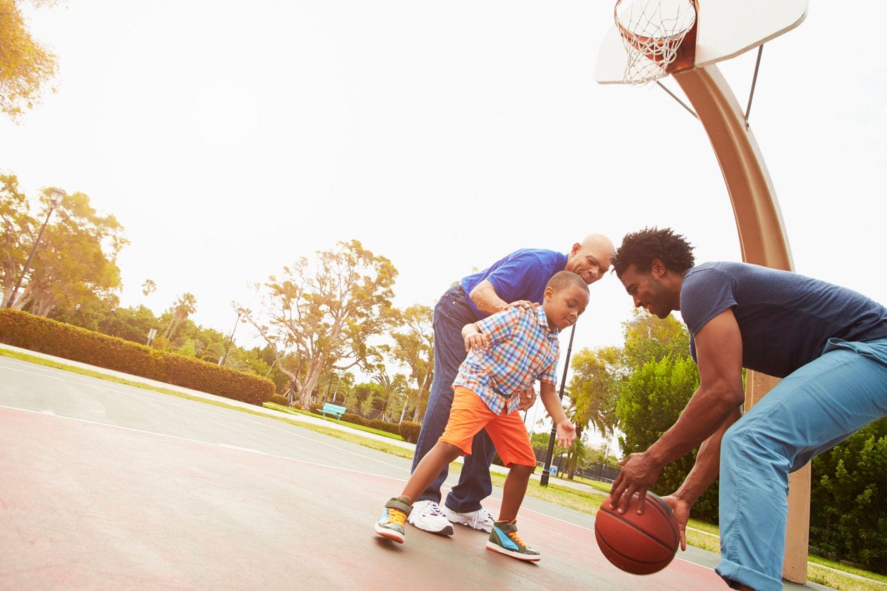 two men playing basketball with young child