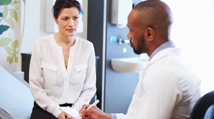 concerned female patient talking to doctor in exam room