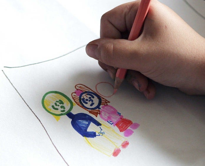 close up of a child's hand drawing with colored pencils