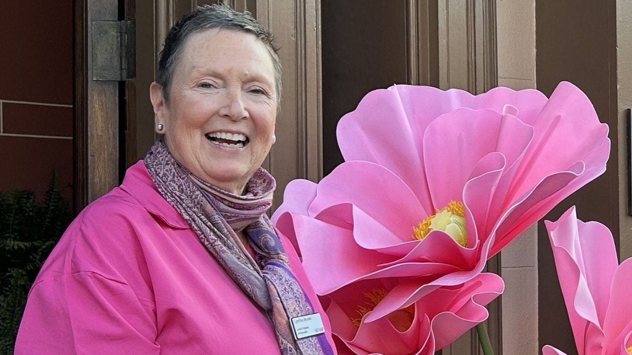 Cyndi Bruner smiles with a large pink flower