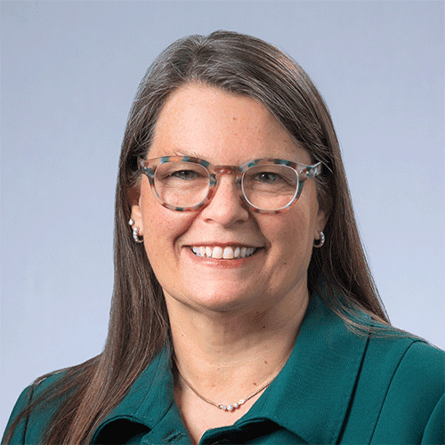 Smiling woman in green top and glasses, headshot.