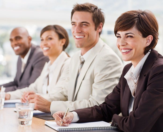 An image of a business team attending a meeting and smiling. A mixed handsome group paying attention.