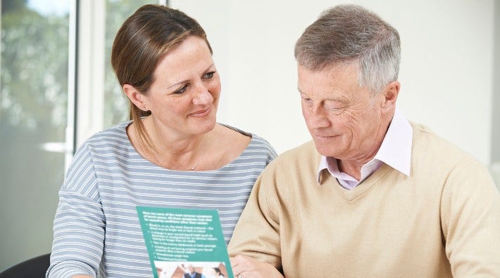 adult daughter shows her father a pamphlet