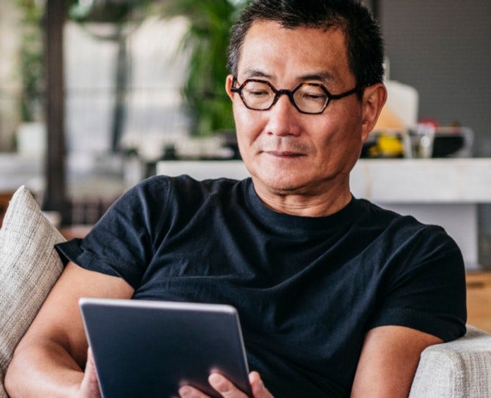 asian man in his 50s looking at tablet