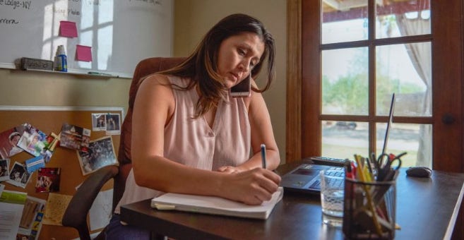 women talking on the phone and writing in notebook