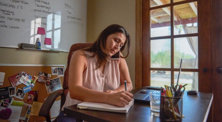 women talking on the phone and writing in notebook