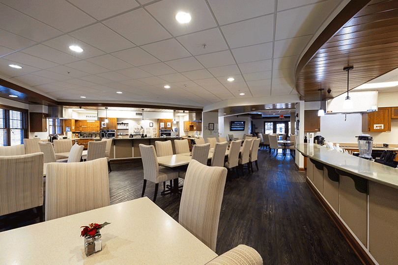 Dining area with tables, chairs, and open kitchen counter.