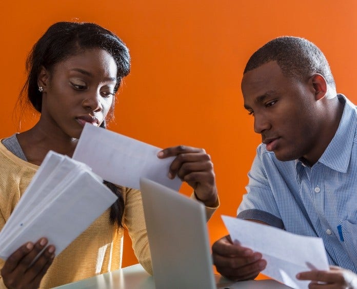 worried couple sorting paperwork and bils at computer