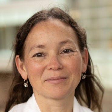 woman with long brown hair with white jacket, sparkling earrings and necklace