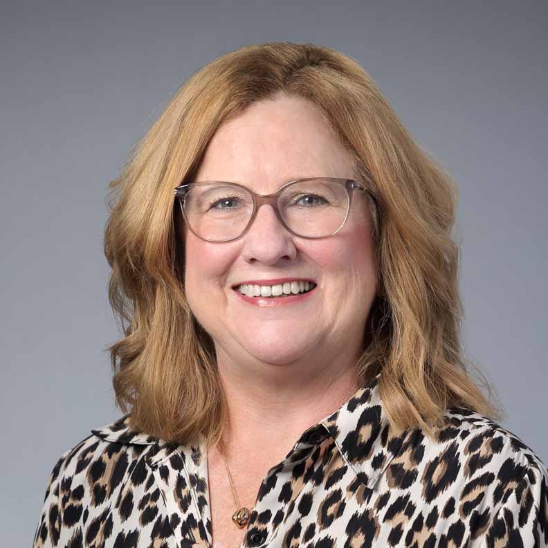 Smiling woman wearing glasses and leopard print blouse.