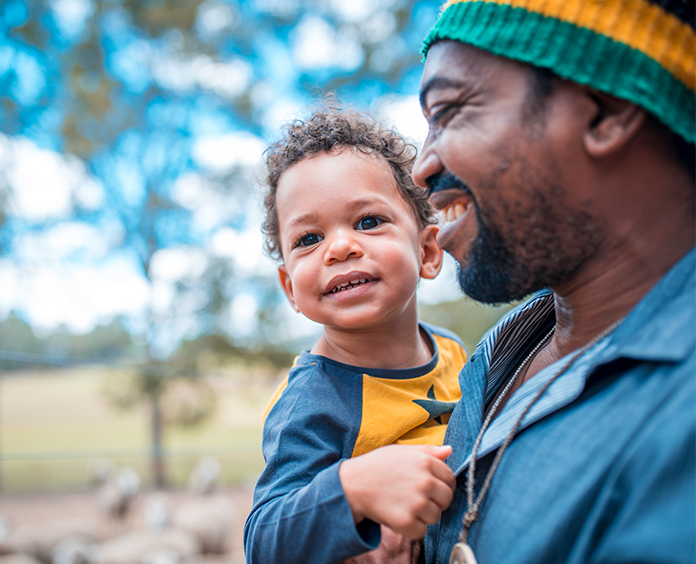 Black father holding son outdoors