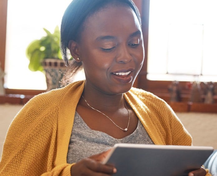 woman holding a tablet while sitting in the lounge of her home