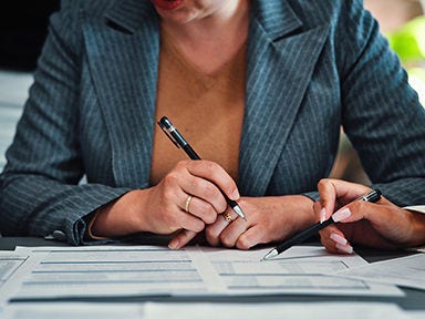 A close up of a person holding a pen looking at papers