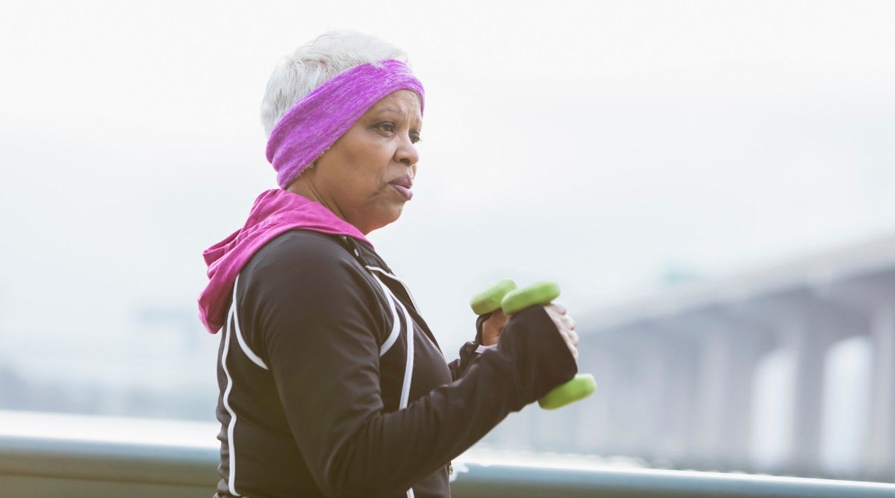 Senior woman walks outside with hand weights