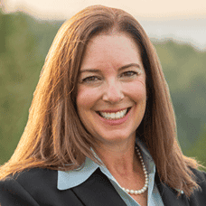 Smiling woman in blazer with pearl necklace outdoors