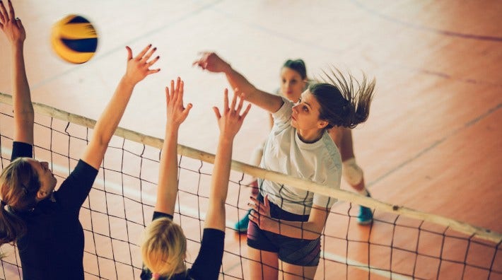Young women playing volleyball inside gym