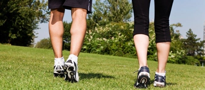 man and woman in exercise gear walk through park