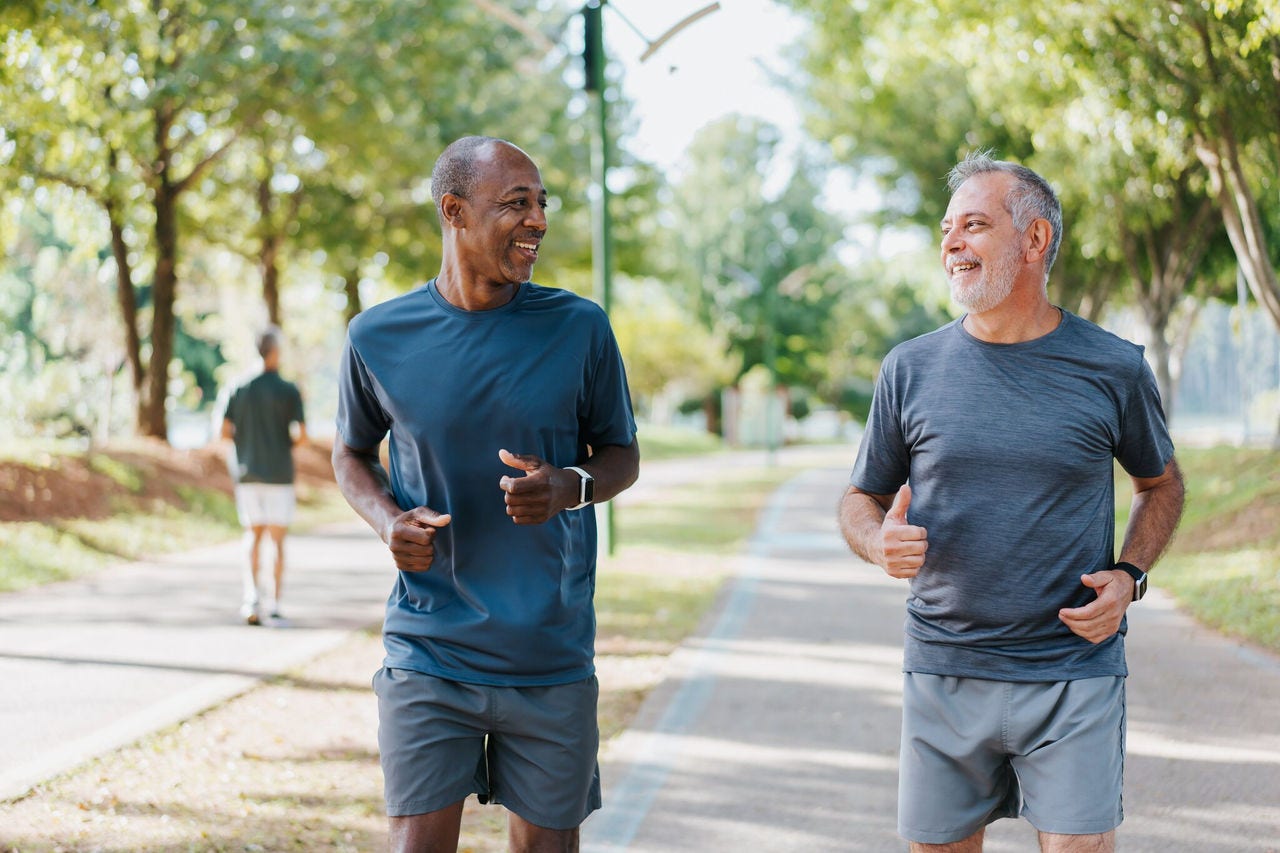 Two men jog together in park