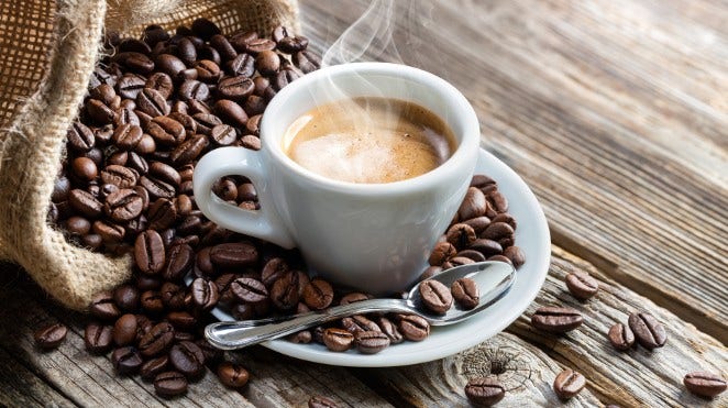 cup of hot espresso on table with a burlap sack of coffee beans