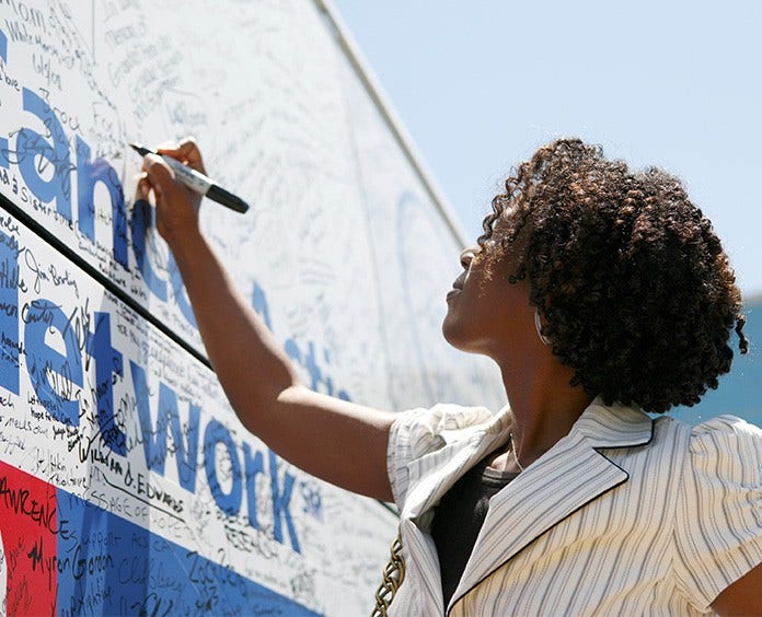 Black woman signing her name on signature board