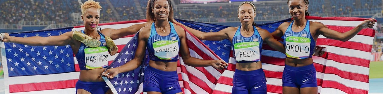 Four Olympic Track and Field stars with American flag posing for camera