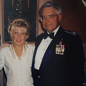 Older couple posing together, man in formal military uniform.