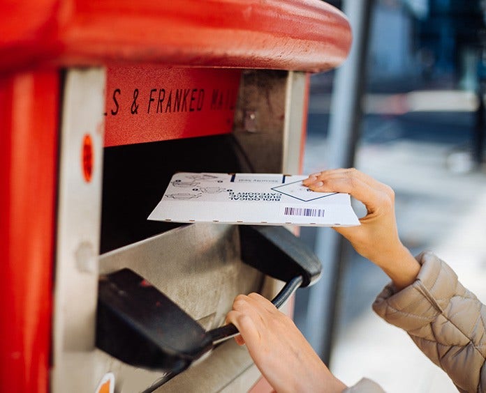 Hands mailing letter in red mailbox envelope says biological upside down