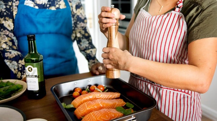 close up of woman's hands as she seasons salmon