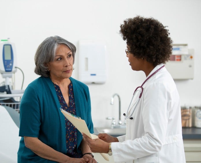 female doctor speaks with female patient in exam room